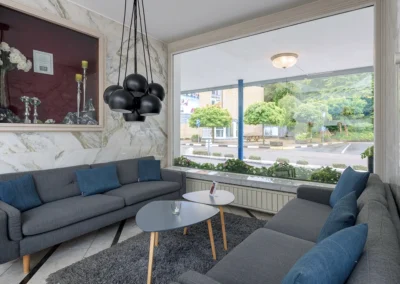 Sitzbereich mit Sofas in der Hotellobby vor großem Fenster mit Blick nach draußen.
